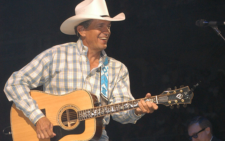 George Strait playing a guitar on stage.